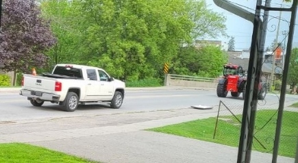 Two suspect vehicles, a white pick-up truck and a red tractor, are seen in recent surveillance footage. Police say three suspects driving these vehicles are suspected in a case of theft and mischief where multiple pride flags were defaced and stolen in Norwich Township on May 20 and 21. (Source: Oxford County OPP)