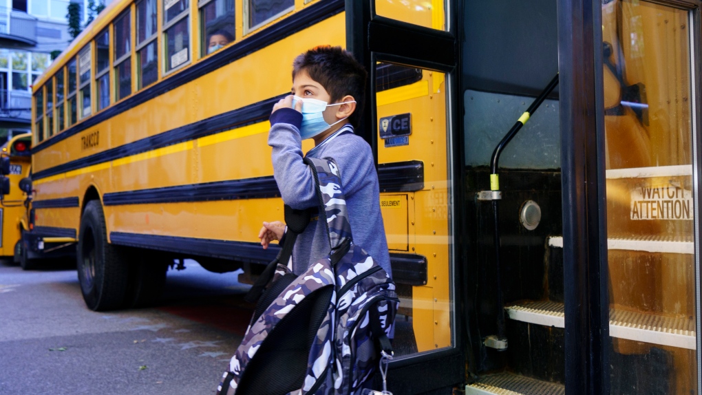 A student adjusts his protective mask as he walks off the bus at the Bancroft Elementary School as students go back to school in Montreal, on Monday, August 31, 2020. (THE CANADIAN PRESS/Paul Chiasson)